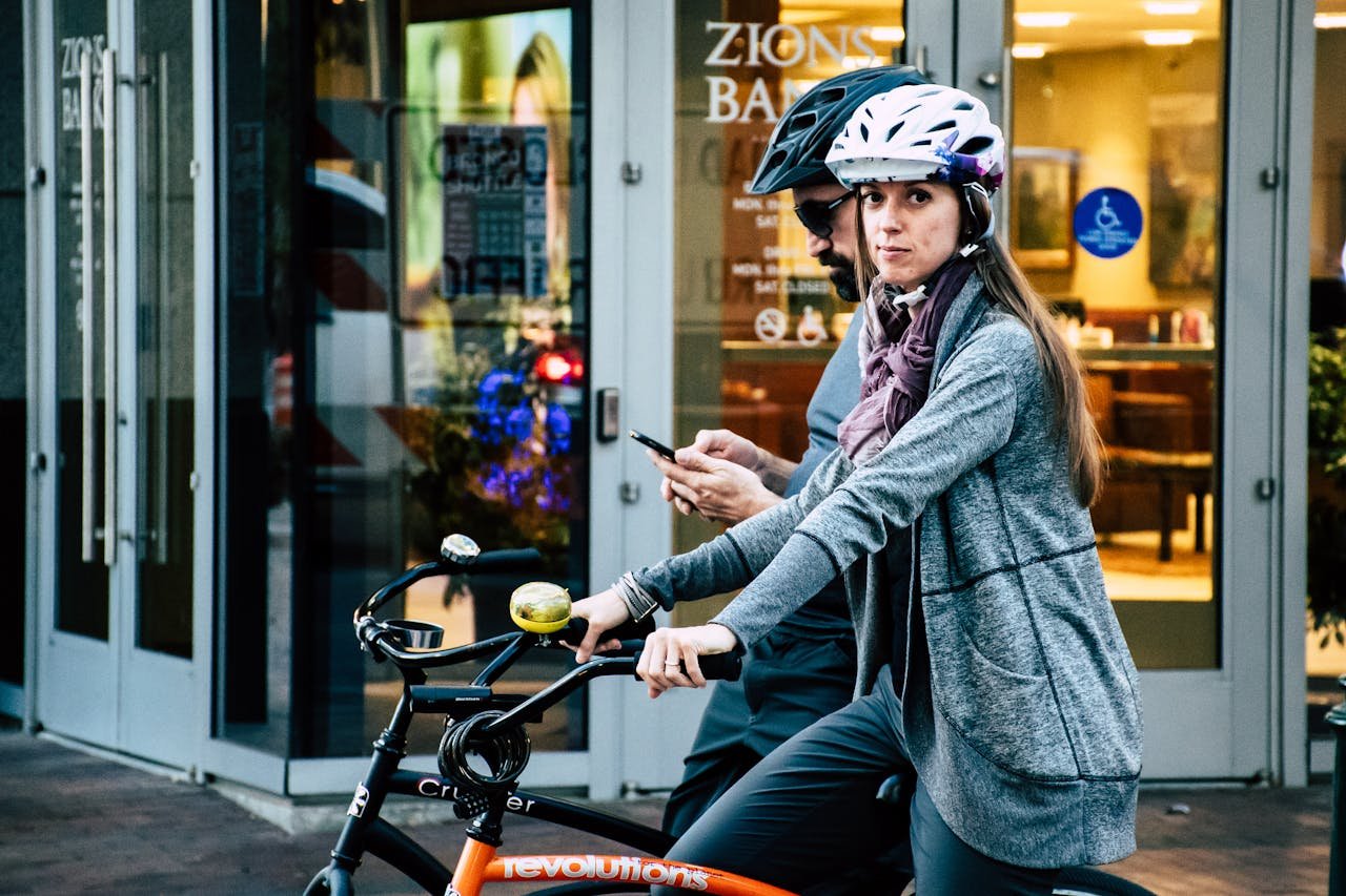 Man and woman on bicycles using phones outside a city shop