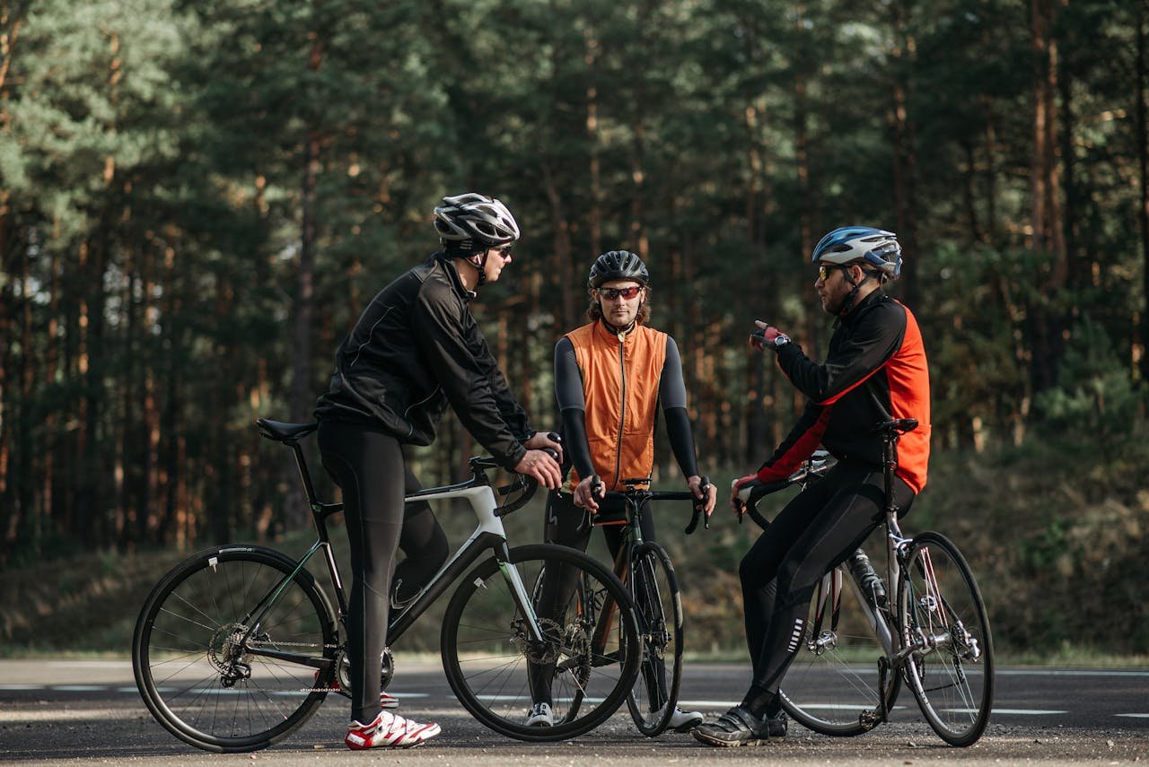 Three cyclists in activewear having a conversation on a forest road.